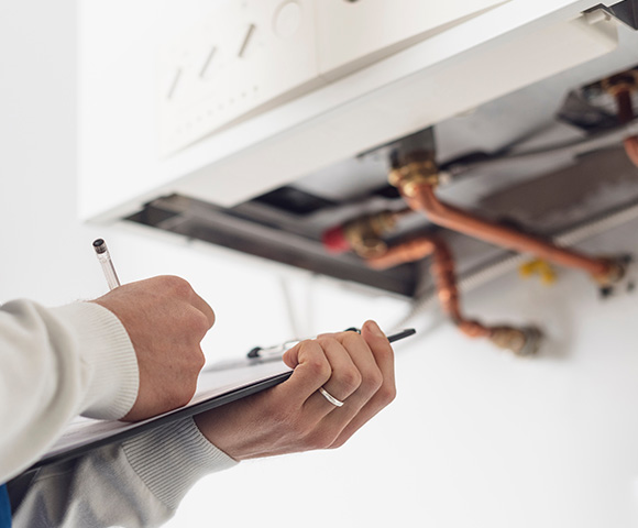 person inspecting plumbing system and taking notes for two maintenance checks