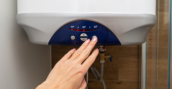 hand adjusting temperature settings on a water heater with 4 available temperature options