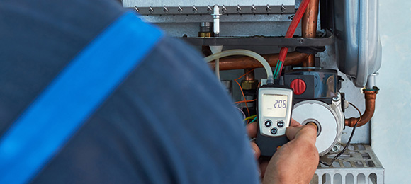 technician using digital pressure gauge on heating system equipment for maintenance and repairs